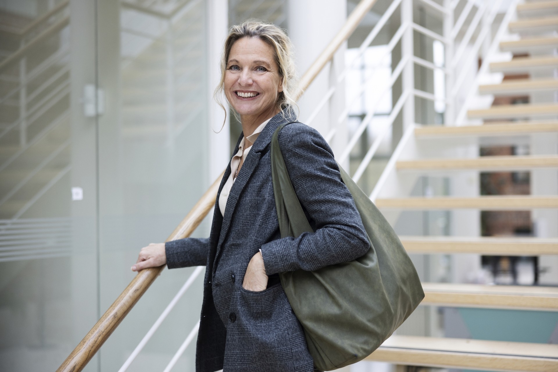 Lachende vrouw loopt via een trap naar beneden en heeft een bouwdepot aangevraagd om haar vastgoedobject te verduurzamen.